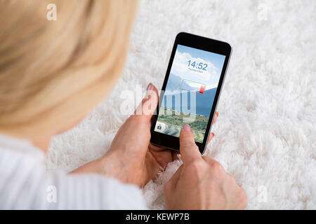 In der Nähe von Frau hand Handy mit schwacher Batterie auf dem Teppich Stockfoto