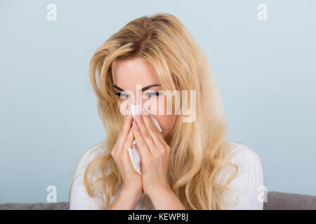 Porträt einer Frau mit Allergie oder Grippe niesen Nase in Seidenpapier auf der Couch Stockfoto