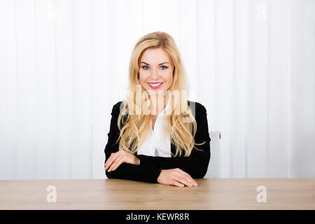Porträt Einer jungen lächelnden Geschäftsfrau, die am Schreibtisch sitzt Stockfoto