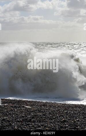 Ocean Waves crash auf einen Kiesstrand in Newhaven in East Sussex, England. Stockfoto