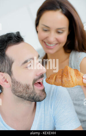 Mädchen geben Croissant für Mensch Stockfoto