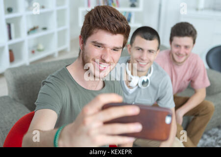 Drei glückliche Teenager Männer, die selfie mit Smartphone Stockfoto