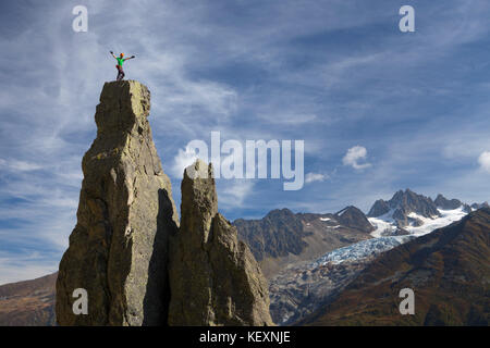 Ein Bergsteiger, der auf einem Gipfel hoch über Chamonix in den französischen Alpen steht. Im Hintergrund befindet sich der Argentiere Gletscher. Stockfoto