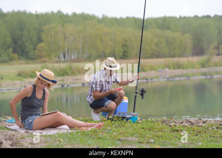 Junges Paar Fischen oder Angeln auf dem Lake Shore Stockfoto