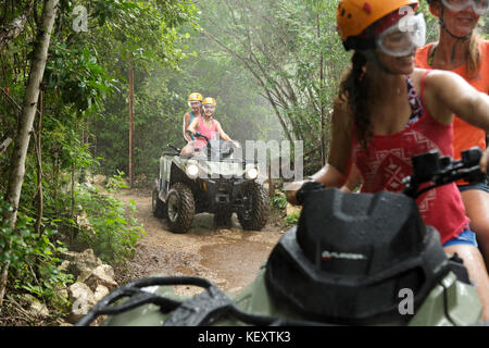 Frauen fahren Quad Bikes in Emotionen Native Park bei Regen, Quintana Roo, Mexiko Stockfoto