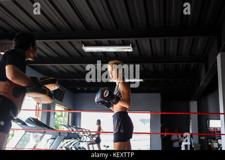 Foto von jungen weiblichen Kickboxer in Kampfstellung im Ring mit Trainer, Seminyak, Bali, Indonesien Stockfoto