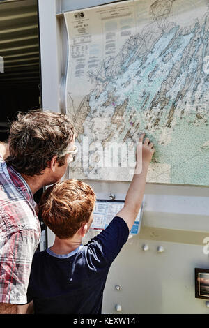 Vater und Sohn untersuchen Karte hängen an der Wand, Portland, Maine, USA Stockfoto