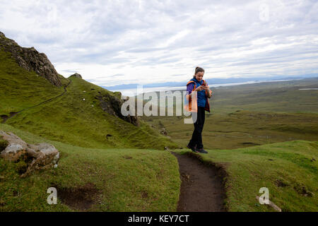 Schottisches Hochland, Isle of Skye. Cuith-Raing oder Quiraing. Wanderer macht ein Panoramabild mit ihrem Handy. Stockfoto