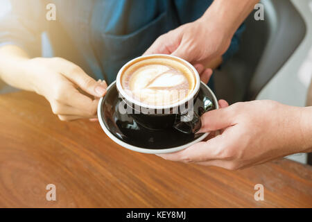 Close-up Hand einer Kellnerin, um eine Tasse Kaffee zu Kunden dienen. Selektive konzentrieren. Stockfoto