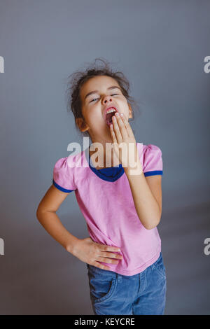 Mädchen legte ihre Hand auf ihren Mund, gähnt Stockfoto