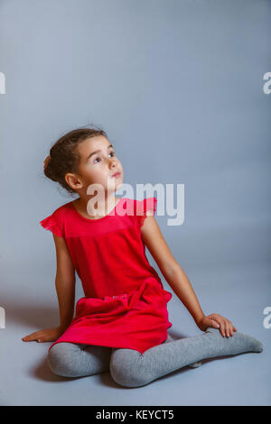 Ruhig Mädchen Teenager sitzt in einem roten Kleid auf der Seite auf einem Stockfoto