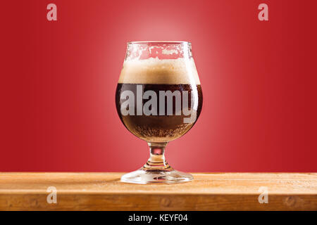 Glas kalten schaumigen dunkles Bier auf einem alten Holztisch Stockfoto
