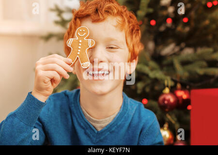 Adorable lockigen Haaren Kind spielt mit Gingerbread Man Stockfoto