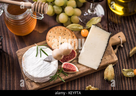 Käseplatte mit Crackern, Feigen und Trauben und Honig. Stockfoto