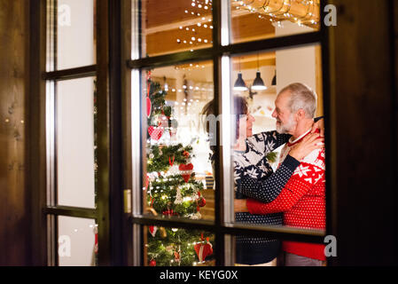 Schönes älteres Ehepaar im Wollenen Pullovern mit nordinc Muster zur Weihnachtszeit. Schuß durch Glas. Stockfoto