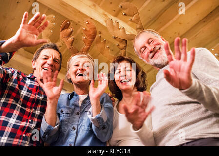 Ältere Freunde mit Rentier Geweih Stirnbänder zu Weihnachten, winken und Spaß haben. Stockfoto