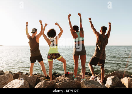 Zurück Blick auf vier happy Fitness freuen sich nach dem Training in der Nähe des Meeres Stockfoto