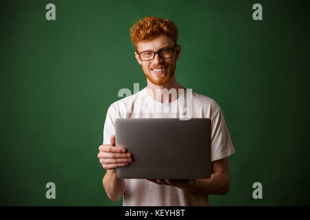 Ein Porträt der jungen Abtastkopf Mann im weißen T-Shirt mit Laptop, Kamera suchen Stockfoto