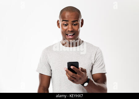 Überrascht afrikanischen Mann mit Smartphone auf weißem Hintergrund Stockfoto