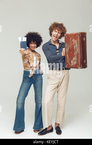 Bild von jungen retro Paar isolierten posieren. Suchen Kamera holding Koffer Passport und Tickets. Stockfoto