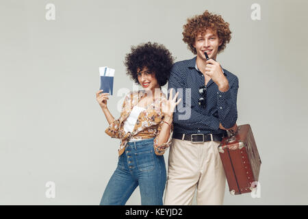 Bild von jungen retro Paar isolierten posieren. Suchen Kamera holding Koffer Passport und Tickets. Stockfoto