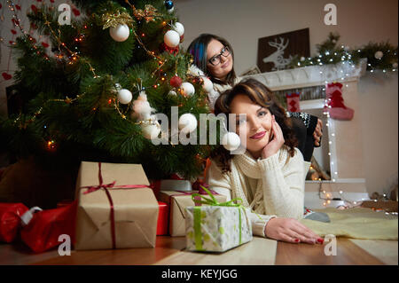 Schöne Frau und ihre Tochter ruhen unter dem Weihnachten tre Stockfoto