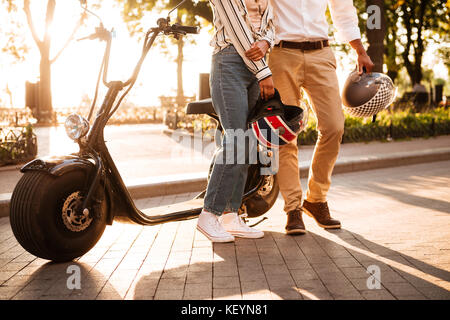7/8 Image der jungen afrikanischen Paar posiert in der Nähe der modernen Motorrad in Park Stockfoto