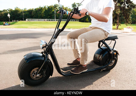 7/8 Seitenansicht des jungen Mann reitet auf modernen Motorrad draußen Stockfoto