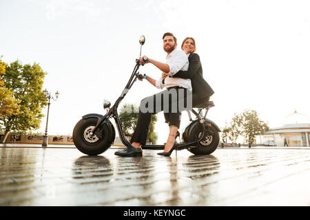 Volle Länge Seitenansicht Bild der freudigen Geschäft paar Fahrten auf moderne Motorräder in Park und Wegsehen Stockfoto