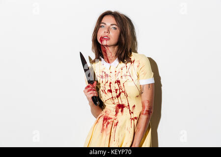 Crazy zombie Frau in Kleid holding Messer, und wenn man die Kamera auf weißem Hintergrund Stockfoto