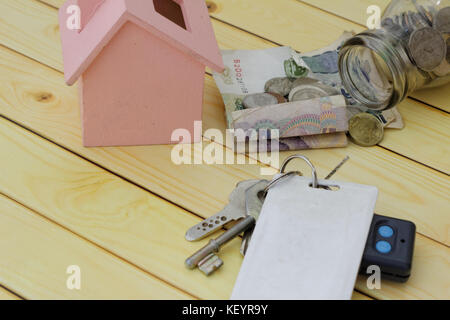 Miniatur-Haus, Geld Auslaufen aus dem Glas, der Schlüssel mit Fernbedienung und Access Card eingestellt. Konzept der Eigenverantwortung, Auktion, Haftung, finanzielle, investieren. Stockfoto