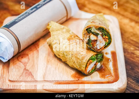 Frische Tortilla Wraps mit Hähnchen und Gemüse auf Schneidebrett. Stockfoto