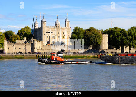 Schlepper mit einem Lastkahn entlang der Themse, vorbei am Tower of London in London. Industrieller Flussverkehr Stockfoto