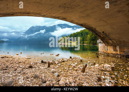 Bohinj See Blick aus unter der Brücke. schönen Gletschersee an einem bewölkten Herbst Tag. Stockfoto