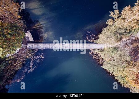 Antenne drone Ansicht auf zwei kleine Inseln auf dem See durch kleine Holzbrücke verbunden. Herbst am See Stockfoto