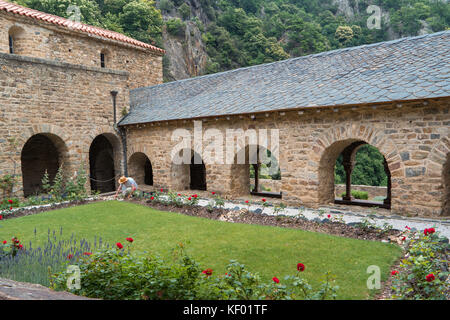 Gärtner im Garten des Kreuzgangs der romanischen Abtei von Saint Martin du Canigou in den französischen Pyrenäen Stockfoto