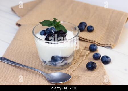 Glas Tasse Joghurt mit Blaubeeren und Minzeblättchen Stockfoto