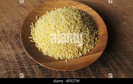 Trockene Bulgur weizen in Houten isoliert verschüttete Bulgur Stockfoto