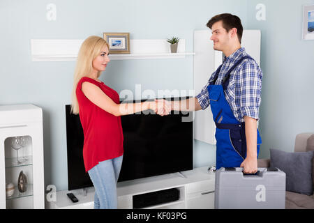 Junge männliche Techniker zitternden Hand mit lächelnden jungen Frau zu Hause Stockfoto