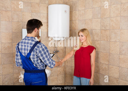 Junge Frau die Hände schütteln mit männlichen Klempner im Bad zu Hause Stockfoto