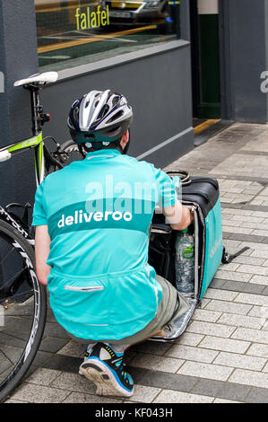 Weibliche Deliveroo Mitarbeiter prüft Ihre Box von Lebensmitteln vor Auslieferung an Ihre Kunden in Cork, Irland. Stockfoto