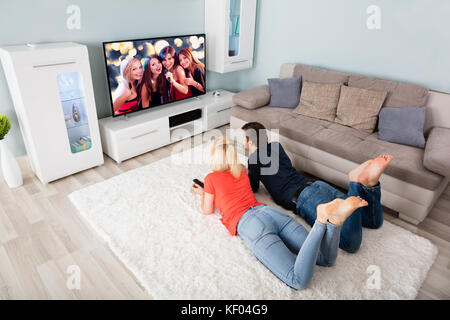 Junges Paar Liegen auf dem Teppich vor dem Fernseher zu Hause Stockfoto