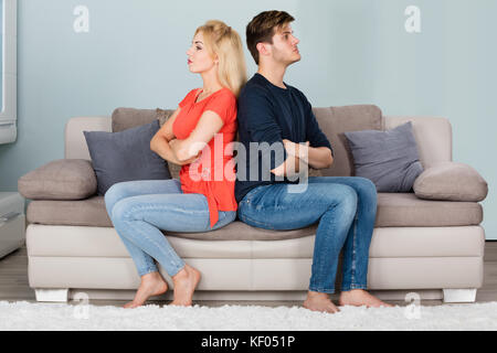 Junges Traurtes Paar Im Kampf Mit Gekreuzten Armen Auf Sofa Sitzend Nach Streit Zu Hause Stockfoto