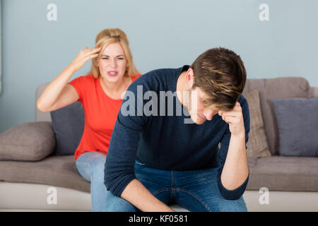 Unglückliche Junge Frau, Die Auf Der Couch Sitzt Und Sich Mit Dem Mann Zu Hause Gestritten Und Gestritten Hat Stockfoto