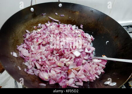 Frittieren rote Zwiebeln in Stahl wok Stockfoto