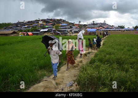 Rohingya-flüchtlinge Spaziergang durch ein Reisfeld am palongkhali provisorischen Lager in Cox's Bazar, Bangladesch, am Oktober 06, 2017. Entsprechend der Uni Stockfoto