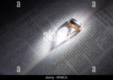 Gold Ring auf ein Buch casting ein Herz shapped Schatten. Stockfoto