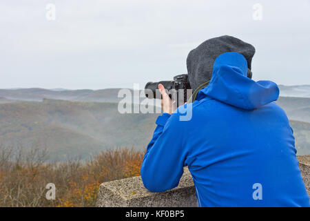 Fotograf nimmt ein Foto auf einem Berg im Wienerwald auf einem nebligen und trüben Herbsttag. Stockfoto