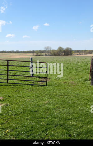 Einen Üppigen, grünen, malerischen Bauernhof und verrostete Tor auf einem klaren blauen sonnigen Tag. Stockfoto