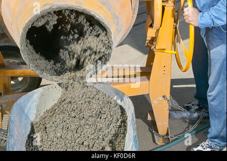 Eine Nahaufnahme einer Person gießen nassen Zement in einer Schubkarre in einem diy, home Bau themed Bild. Stockfoto